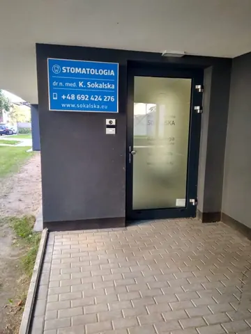 Drzwi wejściowe do gabinetu i niebieski szyld Stomatologia.